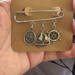 Nautical themed pin with sailboat, ship's wheel and anchor